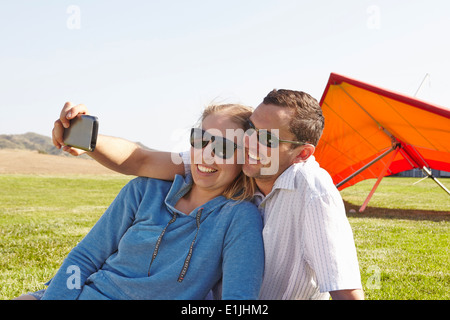 Couple taking selfie, hang glider in background Stock Photo