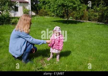mother sits in the meadow daughter gather the small white daisies and give mom Stock Photo