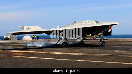 An X-47B unmanned combat air system demonstrator completes an arrested landing on the flight deck of the aircraft carrier USS G Stock Photo