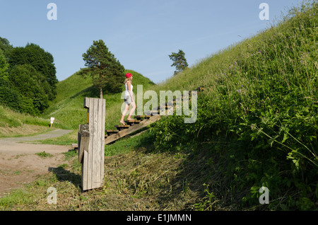 Young tourist girl climb on mound hills in Lithuanian historic capital Kernave, UNESCO World Heritage Site. Stock Photo