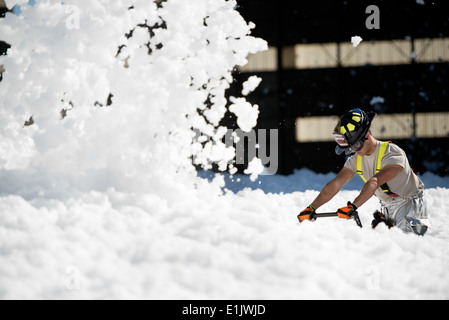 U.S. Air Force Senior Airman Allen Stoddard, with the 60th Civil Engineer Squadron, blows a small sea of fire-retardant foam th Stock Photo