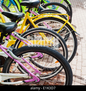 Colorful bicycles stand in row on a parking lot for rent Stock Photo