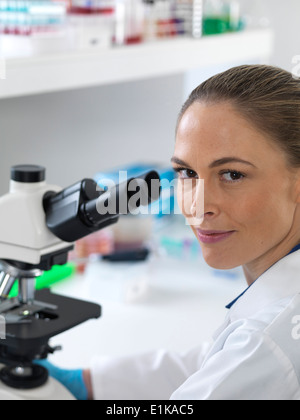 Portrait of female scientist by a microscope. Stock Photo