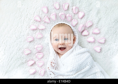 MODEL RELEASED Baby boy wrapped in blanket with heart shapes around his head. Stock Photo