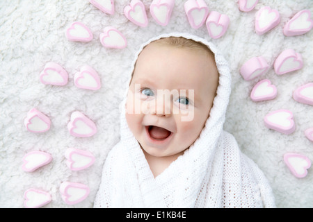 MODEL RELEASED Baby boy wrapped in blanket with heart shapes around his head. Stock Photo