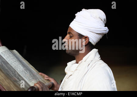 Priest reading a Bible at St. Yimrhane Kristos cave church Stock Photo