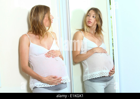 Pregnant woman looks at her reflection in a mirror Model Release Available Stock Photo