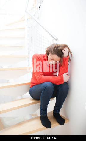 MODEL RELEASED Woman with her hand in her hair on a staircase. Stock Photo