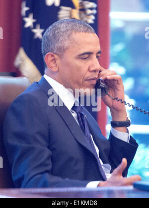 As seen through an outside window looking into the Oval Office, United States President Barack Obama speaks on a conference call hosted by the American Lung Association and other public health groups to discuss new commonsense steps to reduce carbon pollution from power plants in Washington, D.C. on Monday, June 2, 2014. Credit: Ron Sachs / Pool via CNP Stock Photo