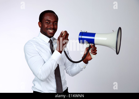 African man shouting through a megaphone on gray background Stock Photo