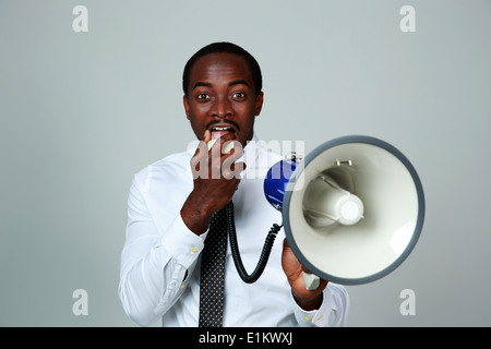 African man shouting through a megaphone on gray background Stock Photo