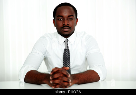 Thoughtful african man sitting at the table in office Stock Photo