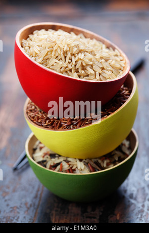 Three bowls with different types of rice on wooden background Stock Photo