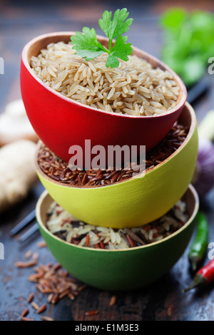 Three bowls with different types of rice on wooden background Stock Photo