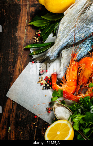 fresh dorado fish and shrimps on wooden board with ingredients Stock Photo