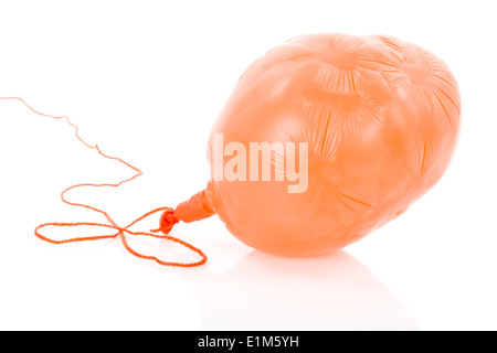 Deflated orange balloon at a rope; isolated over white background Stock Photo