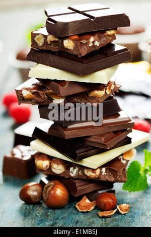 An assortment of white, dark, and milk chocolate with nuts on wooden background Stock Photo