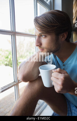 Thoughtful man sitting by the window having coffee Stock Photo