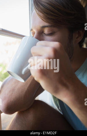 Handsome man sitting by the window having coffee Stock Photo