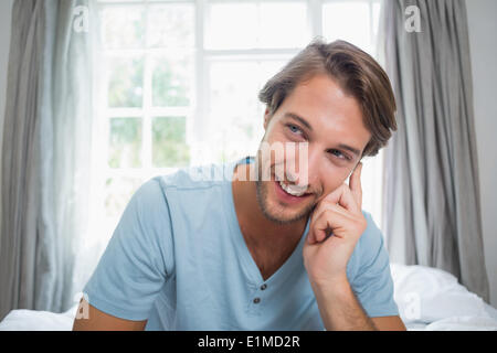 Handsome smiling man sitting on bed Stock Photo