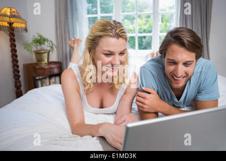 Cute couple relaxing on bed using the laptop Stock Photo