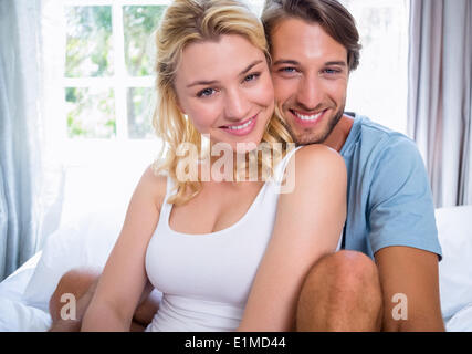 Cute young couple relaxing on bed smiling at camera Stock Photo