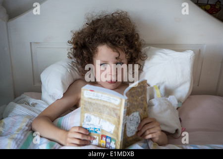 Girl reading book in bed Stock Photo