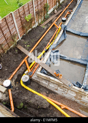 self building house, drainage pipes and yellow gas supply duct being laid around site Stock Photo