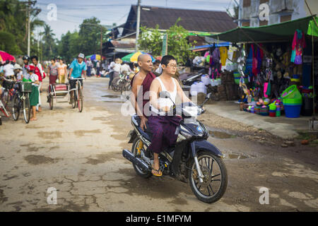 June 6, 2014 - Pantanaw, Ayeyarwady Region, Myanmar - A man brings a Buddhist monk into Pantanaw on a motorcycle. Pantanaw is a town in the Irrawaddy Delta (or Ayeyarwady Delta) in Myanmar. The region is Myanmar's largest rice producer, so its infrastructure of road transportation has been greatly developed during the 1990s and 2000s. Two thirds of the total arable land is under rice cultivation with a yield of about 2,000-2,500 kg per hectare. FIshing and aquaculture are also important economically. Because of the number of rivers and canals that crisscross the Delta, steamship service is wid Stock Photo