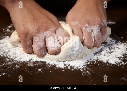 woman's hands kneading dough on wooden table Stock Photo