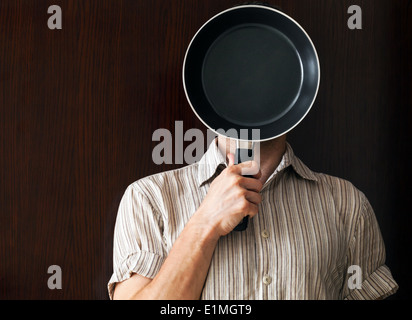 Young man portrait behind black frying pan Stock Photo