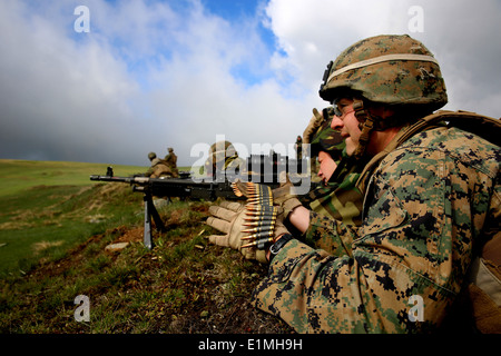 A Romanian soldier with the 17th Mountain Troop Battalion fires an M240B machine gun with U.S. Marine Corps Lance Cpl. Dylan Ha Stock Photo