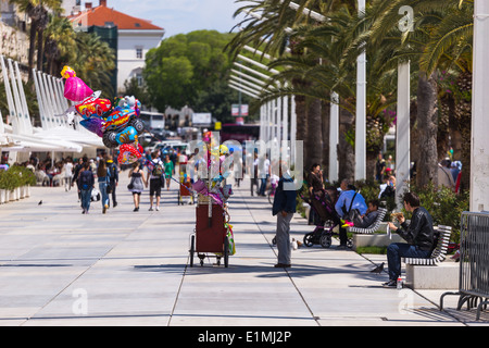 Local people and tourists walk along the Riva in split croatia. Cafes and restaurants line the side. balloons float in the wind Stock Photo