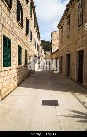 A shaded back street in vis town showing contrast between green shuttered windows and brown doors on each side Stock Photo