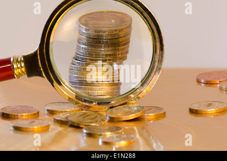 A stack of coins, increased under a magnifying glass Stock Photo