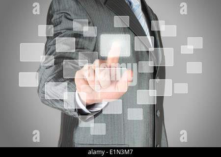 Businessman with hand using virtual inteface on grey background Stock Photo