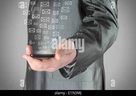 Businessman uses smart phone with virtual envelopes on grey background Stock Photo