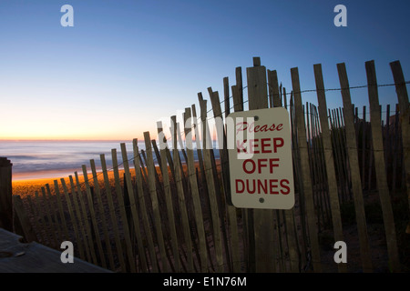 Sunrise over the beach with sign on the fence reminding people to keep off the dunes Stock Photo