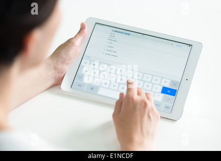 Woman holding a white Apple iPad Air and typing for search Google web page in Safari browser Stock Photo