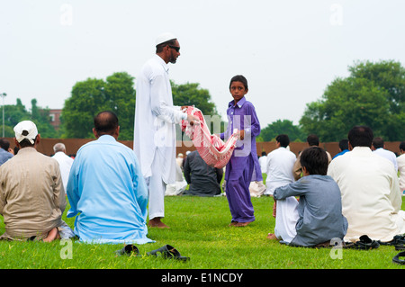 Child and blind Adult beggars in between people sitting for prayers on Eid, Lahore, Pakistan Stock Photo