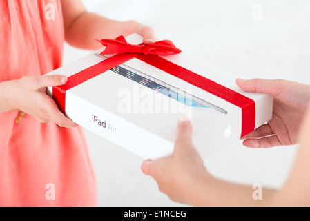 Mother gives her daughter a birthday present — brand new Apple iPad Air in a festive packaging. Stock Photo