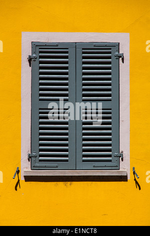 Grey shutters on a bright yellow wall in Sion, Switzerland Stock Photo