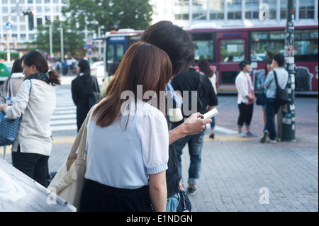 Tokyo, Japan 2014 - Couple using mobile phone on the street Stock Photo