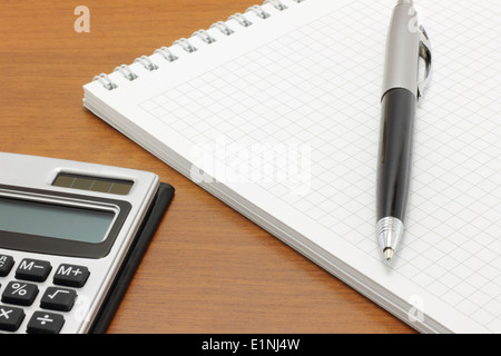 Notepad with pen and calculator on a wood background Stock Photo