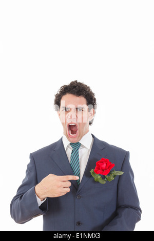 adult angry and shocked man in suit with disgust face expression showing with his hand rose flower which is in his jacket pocket Stock Photo