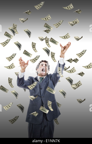 excited man catching money falling around him, businessman under money rain, yelling man reaching for flying banknotes Stock Photo