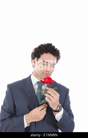 handsome man seducer in a business suit holding rose in his hand and smelling it, isolated on white background Stock Photo