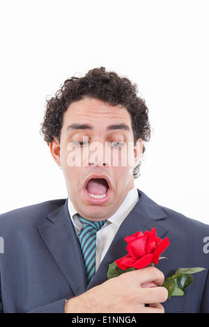 adult shocked man in suit with weird face expression holding with his hand rose flower which is in his jacket pocket Stock Photo