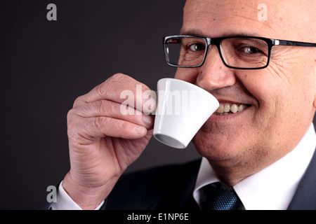 bald old smiling businessman holding a cup of espresso italian coffee Stock Photo