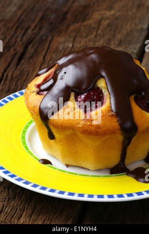 Vanilla cake with sour cherries and dark chocolate on yellow plate rough dark wooden background Stock Photo